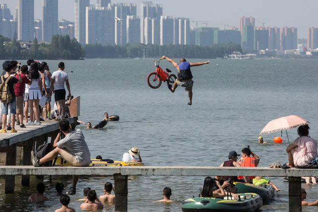A participant jumps into a lake with a bike during a local event to call on residents to protect the  environment in Wuhan, Hubei Province, China, July 24, 2016. (Photo by Reuters/China Daily)