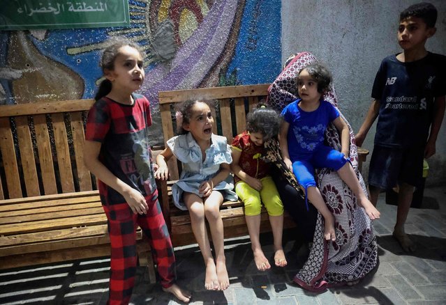 Palestinian children react as they wait outside a hospital following a reported Israeli strike in Rafah in the southern Gaza Strip, late on August 6, 2022. (Photo by Said Khatib/AFP Photo)