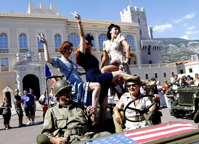 People dressed in 1940's fashion parade on a US military vehicle in front of Monaco Palace as part of the commemoration of the 70th anniversary of the liberation of Monaco in the second World War, on September 3, 2014 in Monaco. (Photo by Valery Hache/AFP Photo)