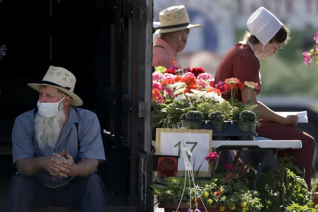 Vendors wait for customers at a drive-thru farmers market Saturday, May 2, 2020, in Overland Park, Kan. The market has moved from its usual home to a sprawling parking lot allowing for people to spread out and shop from their cars as a measure to stem the spread of COVID-19. (Photo by Charlie Riedel/AP Photo)