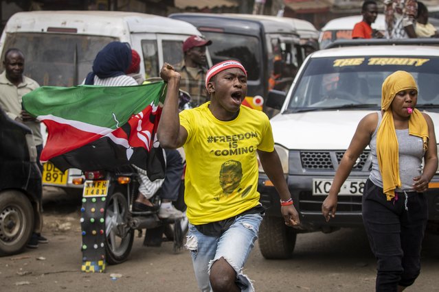 A supporter runs through the streets wearing a t-shirt showing William Ruto, and waving the national flag, in the Kibera neighborhood of Nairobi, Kenya, Monday, September 5, 2022. (Photo by Ben Curtis/AP Photo)