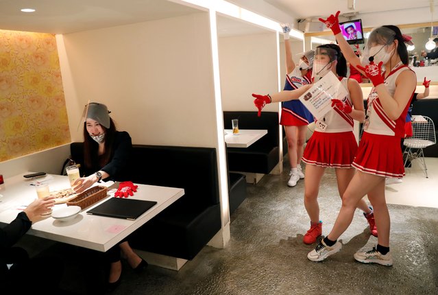 Waitresses wearing protective masks, face-shields and gloves to prevent infections following the coronavirus disease (COVID-19) outbreak, gesture to customers toasting glasses at the cheerleader-themed restaurant “Cheers One” in Tokyo, Japan on May 11, 2020. (Photo by Kim Kyung-Hoon/Reuters)
