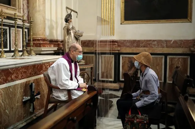 A priest wearing a protective face mask listens to a confession inside the Cathedral, as some Spanish provinces are allowed to ease lockdown restrictions during phase one in Valencia, Spain on May 19, 2020. (Photo by Nacho Doce/Reuters)