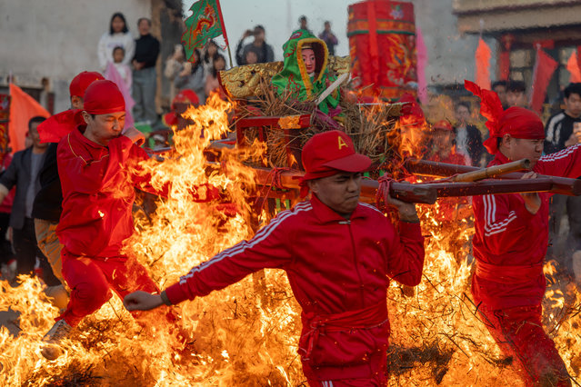 Local people carrying a statue of god jump over a bonfire to pray for blessings on the seventh day of the Spring Festival, or the Chinese New Year, on February 4, 2025 in Jieyang, Guangdong Province of China. (Photo by Wang Zilian/VCG via Getty Images)
