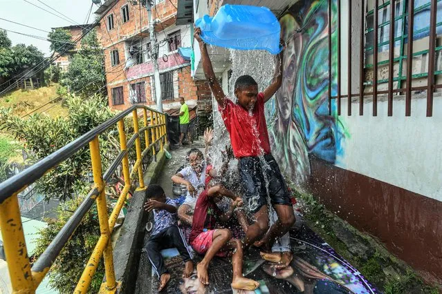 Local children play with water at the Comuna 13 neighbourhood in Medellin, Colombia, on September 28, 2022. One word sums up the history of Medellin over the last twenty years: metamorphosis. After the dark decades of 1970-2000, Colombia's second-largest city is now a transformed, peaceful, dynamic, and attractive city. And one neighborhood, more than any other, symbolizes this renaissance: the famous “Comuna 13”. (Photo by Joaquín Sarmiento/AFP Photo)