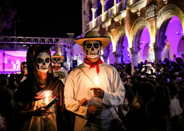 A couple dressed up as Animas, a representation of the souls of the dead by the community of Yucatan, is pictured during the performance of “La Vaqueria de las Animas” in Merida, Yucatan, Mexico on October 31, 2022. (Photo by Camille Ayral/Reuters)