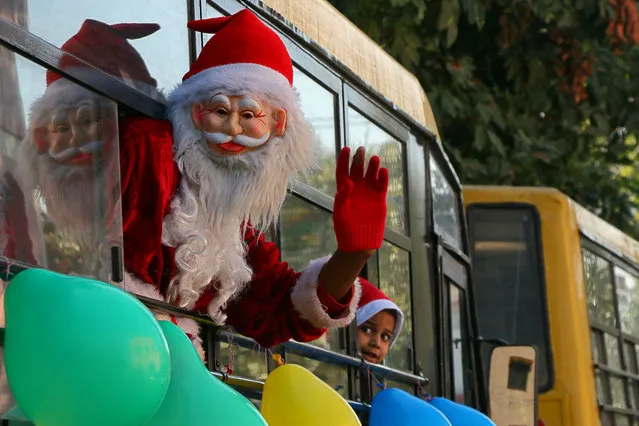 A man dressed in a Santa Claus costume waves from inside a school bus during a procession as part of Christmas celebrations in Chandigarh, India December 23, 2017. (Photo by Ajay Verma/Reuters)