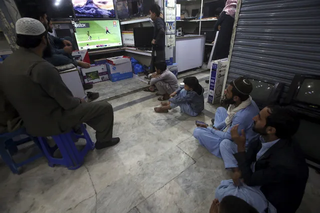 Pakistanis watch the finals match of the T20 World Cup cricket between England and Pakistan on TV at a shop in Peshawar, Pakistan, Sunday, November 13, 2022. (Photo by Muhammad Sajjad/AP Photo)