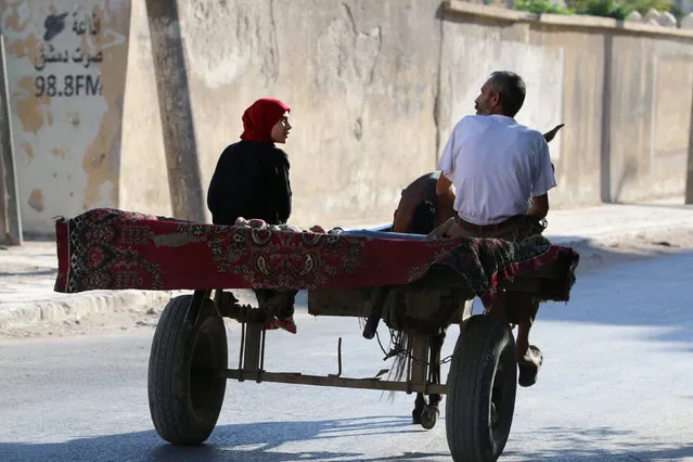 A man and a woman ride a cart in the rebel held al-Maadi district of Aleppo, Syria, August 31, 2016. (Photo by Abdalrhman Ismail/Reuters)