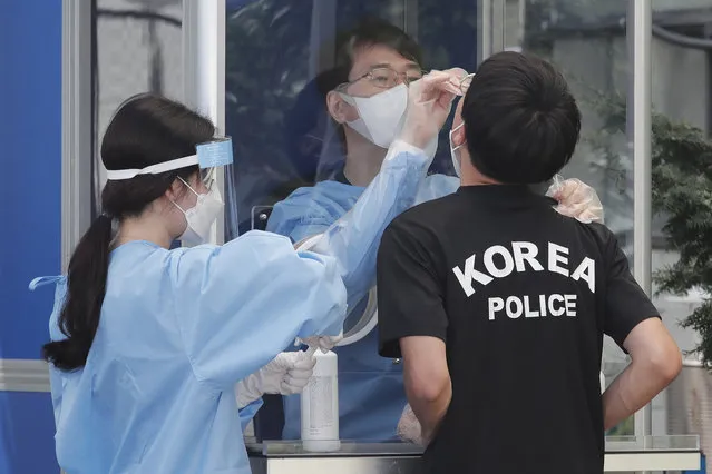 A medical worker takes samples from a police officer during COVID-19 testing at the Seoul Metropolitan Police Agency in Seoul, South Korea, Wednesday, August 19, 2020. (Photo by Ahn Young-joon/AP Photo)