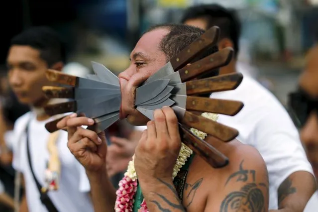 A devotee of the Chinese Samkong Shrine walks with knives pierced through his cheeks during a procession celebrating the annual vegetarian festival in Phuket, Thailand, October 16, 2015. (Photo by Jorge Silva/Reuters)