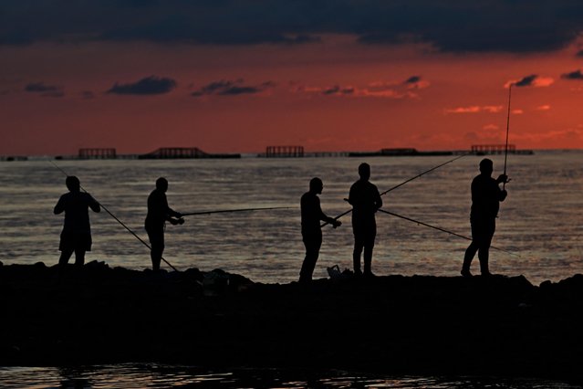 Fishermen stand with their rods on the shore of Black Sea as Turksih salmon cages are seen in the backround in Trabzon on June 10, 2025. From its infancy ten years ago, production of this salmonid species, destined almost exclusively for export, has exploded as global demand for salmon continues to grow, despite criticism of intensive aquaculture. More than 78,000 tonnes of this trout bred on the cold coasts of northern Turkey were exported in 2024, sixteen times more than in 2018. This business brought in over 430 million euros for Turkish producers over the year, a figure set to grow, but still a long way from the 11 billion euros in exports achieved in 2024 by the Norwegian salmon and trout behemoths. (Photo by Ozan Kose/AFP Photo)