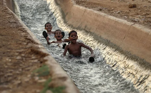 Palestinians slide in a water canal used for irrigation to cool off as temperatures soar in the West Bank city of Jericho to 44 degrees Celsius (111 Fahrenheit) on September 1, 2020. (Photo by Ahmad Gharabli/AFP Photo)