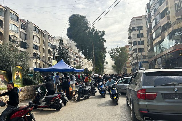 People rush for cover as smoke rises from the site of an Israeli strike in southern Beirut on March 28, 2025. Israel carried out air strikes in southern Lebanon on March 28 after its defence minister threatened Beirut over new rocket fire, rattling an already fragile truce that largely ended more than a year of hostilities with Hezbollah. (Photo by Ibrahim Amro/AFP Photo)