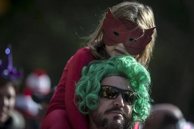 A child rests her head on her father's head as they take part in the Children's Halloween day parade at Washington Square Park in the Manhattan borough of New York October 31, 2015. (Photo by Carlo Allegri/Reuters)