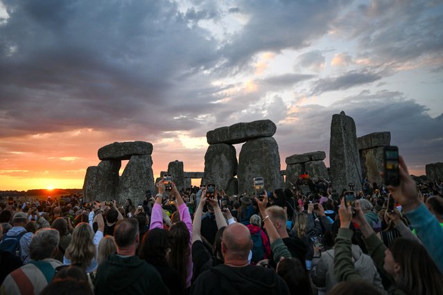 Visitors enjoy the sunrise during celebrations of the summer solstice at Stonehenge, on June 21, 2025 in Wiltshire, England. On the longest day of the year in the Northern Hemisphere, the sun rises in perfect alignment with the Heel Stone and Altar Stone of Stonehenge's 5000-year-old circle. This alignment shows the ancient builders' understanding of the solar calendar and suggests Stonehenge may have served as a calendar or temple for important dates and events – a tradition that continues to be marked each year. (Photo by Finnbarr Webster/Getty Images)