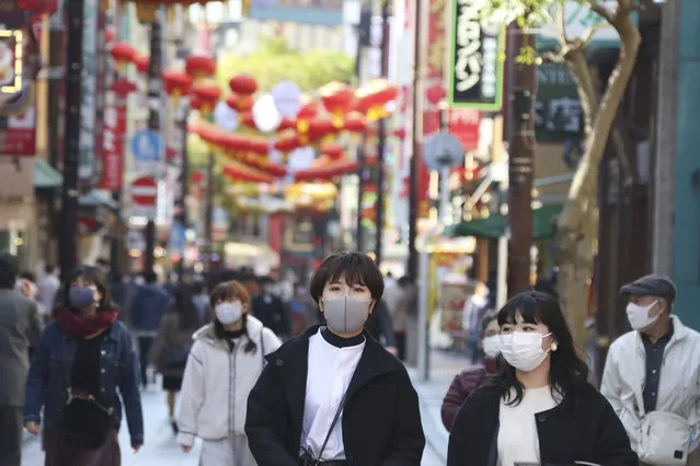 People wearing face masks to protect against the spread of the coronavirus walk through China Town in Yokohama, Kanagawa prefecture, near Tokyo, Tuesday, December 1, 2020. (Photo by Koji Sasahara/AP Photo)