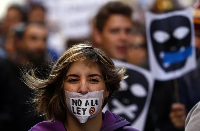 A women with a tape across her mouth reacts during a protest against the Spanish government's new anti-protest security law in Madrid December 20, 2014. A demonstration against Spain's new “Ley Mordaza” anti-protest bill was held on Saturday following its approval by the conservative-led Spanish parliament on December 11 despite heavy opposition from some politicians and activist groups, who say the law violates the right to protest, limits freedom of expression and gives more power to police. (Photo by Sergio Perez/Reuters)