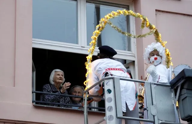 Artists, dressed as clowns, perform from a crane to entertain elderly people at a care home in Prague, Czech Republic, Wednesday, December 16, 2020. As the Czech Republic is facing a rise in new coronavirus infections in December visits of the elderly houses have been limited so the entertainers had to perform through a window. (Photo by Petr David Josek/AP Photo)