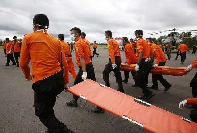 Indonesian Search and Rescue crews walk out to meet a helicopter carrying the bodies of two AirAsia passengers recovered from the sea, at Iskandar airport in Pangkalan Bun, Central Kalimantan, December 31, 2014. (Photo by Darren Whiteside/Reuters)
