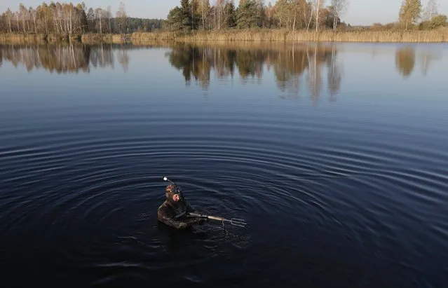 A local diver checks his equipment before diving underwater to hunt on the lake near the village of Tonovo, west of the capital Minsk, Belarus, October 18, 2016. (Photo by Sergei Grits/AP Photo)