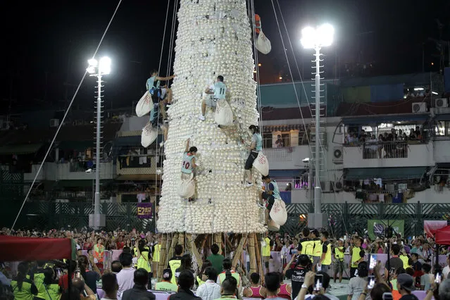 Participants climb up the bun tower during the bun snatching competition on the outlying Cheung Chau island in Hong Kong, Wednesday, May 23, 2018,  to celebrate the Bun Festival. During the Bun Festival, the Taoist God of the Sea, is worshipped and evil spirits are scared away by loud gongs and drums during the procession. The celebration includes bun scrambling, parades, opera performances, and children dressed in colorful costumes. (Photo by Kin Cheung/AP Photo)