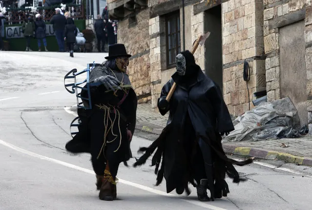 Costumed revelers walk through a street prior to the carnival parade in the village of Vevcani, in the southwestern part of North Macedonia, on Wednesday, January 13, 2021. The coronavirus pandemic has disrupted the usual carnival celebrations which have been taken place for centuries in the tiny North Macedonian town of Vevcani. A few hundred locals gathered at the small town square to celebrate the carnival, but police dispersed the gathering after a brief scuffle with a small group. No arrests or injuries were reported. (Photo by Boris Grdanoski/AP Photo)