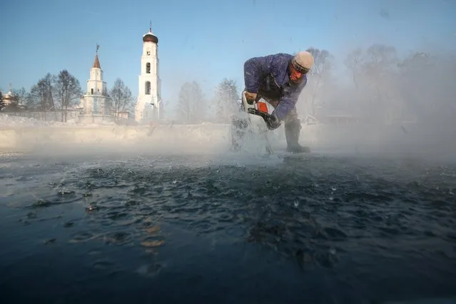 A man carves ice on the frozen Sumka River at the Raifa Virgin Mary Monastery in Tatarstan, Russia on January 12, 2021 to prepare an ice hole for believers who will take a dip in icy waters during the celebration of Epiphany. (Photo by Yegor Aleyev/TASS)