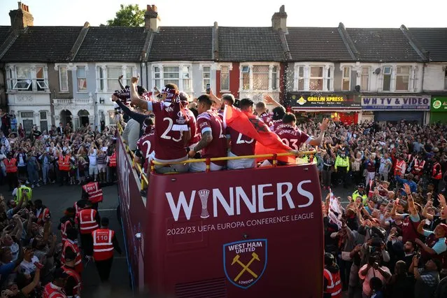 Members of the public gather beneath West Ham United players travelling on an open-top bus, during a parade through the streets of east London on June 8, 2023, to celebrate winning the UEFA Europa Conference League football final. (Photo by Daniel Leal/AFP Photo)