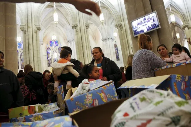 People wait in line during a distribution of free toys for low-income families at Almudena Cathedral in Madrid, Spain, December 22, 2015. (Photo by Susana Vera/Reuters)