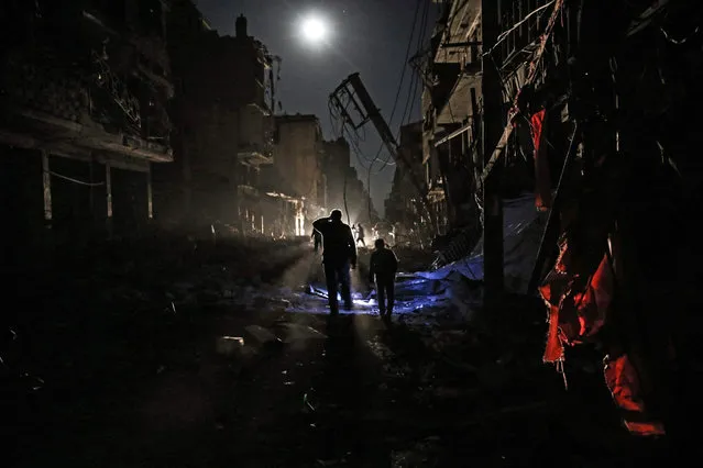 Syrians walk amid debris and destroyed buildings following a reported government airstrike on the rebel-held town of Douma, on the eastern outskirts of the capital Damascus, on late November 17, 2016. Douma, the largest town in the Eastern Ghouta area with more than 100,000 residents, is surrounded and regularly shelled by regime forces. (Photo by Sameer Al-Doumy/AFP Photo)