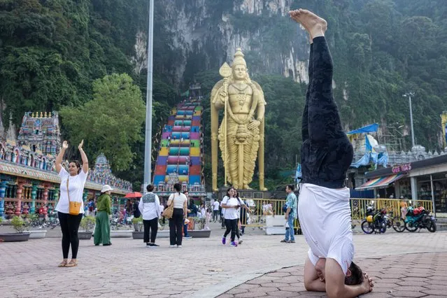 A yoga practitioner performs a headstand in front of Batu Caves on June 21, 2023 in Gombak, Selangor, Malaysia. The event was held as part of the 9th International Day of Yoga. (Photo by Annice Lyn/Getty Images)