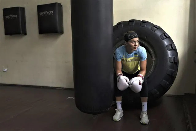 Ukrainian boxer Anna Lysenko sits on a tire while taking a short break during training at Kiko Boxing Club in Kyiv, Ukraine, Tuesday, July 11, 2023. Lysenko dedicates long hours preparing for next year's Paris Olympics despite the unsettling sounds of explosions booming outside. (Photo by Jae C. Hong/AP Photo)