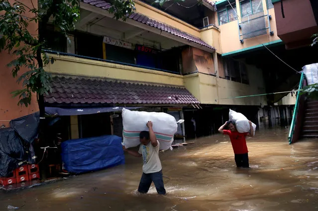 Men carry clothing salvaged from a flooded market in Jakarta, Indonesia, Tuesday, February 10, 2015. (Photo by Tatan Syuflana/AP Photo)