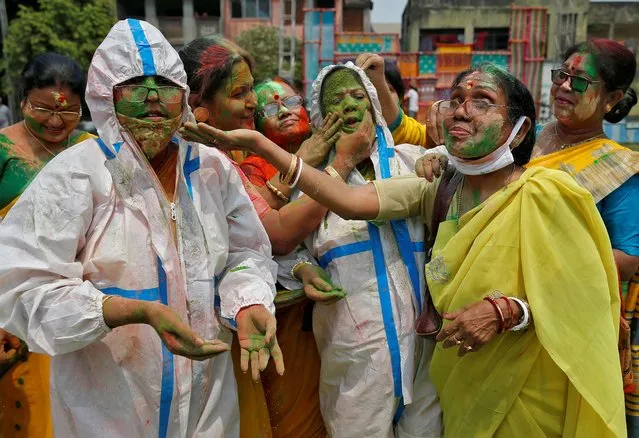 Women wearing protective suits react as coloured powder is applied on their faces Holi celebrations, amidst the spread of the coronavirus disease (COVID-19), in Kolkata, India, March 29, 2021. (Photo by Rupak De Chowdhuri/Reuters)