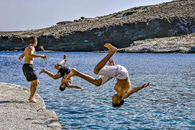 Boys dive into the water at Agios Sostis beach in Serifos island, Greece on July 4, 2023. (Photo by Spyros Bakalis/AFP Photo)