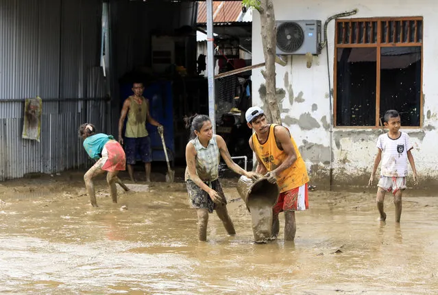 People clear mud off their house in the aftermath of floods in Dili, East Timor, also known as Timor Leste, 05 April 2021. Scores were killed and dozens went missing as floods and landslides caused by torrential rains hit the eastern part of Indonesia and East Timor over the weekend. (Photo by Antonio Dasiparu/EPA/EFE)