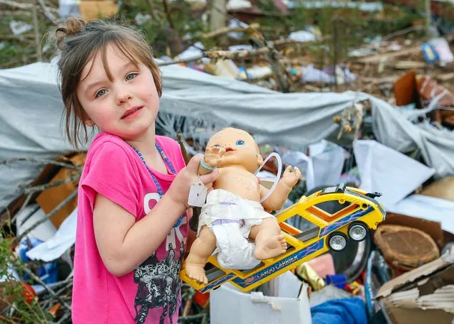 Serenity Brooks, 5, holds a baby doll as she digs for her belongings after a suspected tornado ripped through the town of Rosalie, Ala., November 30, 2016. (Photo by Butch Dill/AP Photo)