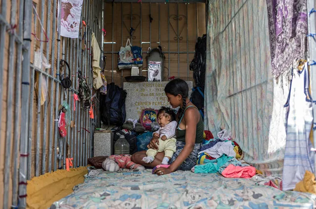 A young woman and a baby rest at a makeshift refuge at the southern general cemetery in Caracas, on February 16, 2021. Desecrated tombs have become the home of many homeless in Venezuela. (Photo by Pedro Rances Mattey/AFP Photo)
