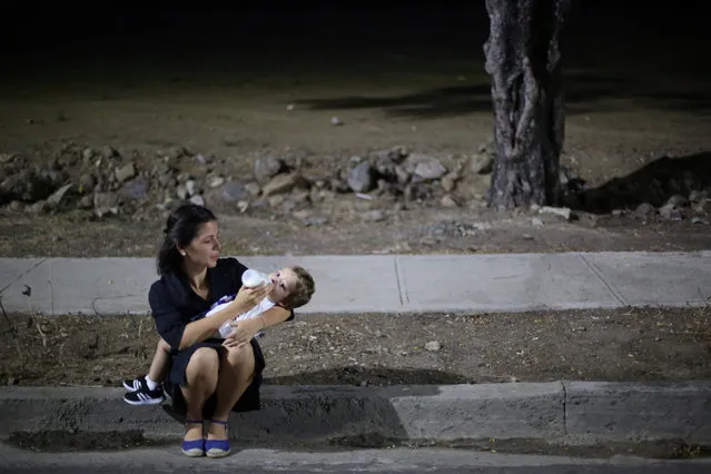 A woman feeds her baby as she awaits the caravan carrying the ashes of Cuba's late President Fidel Castro toward the Santa Ifigenia cemetery in Santiago de Cuba, Cuba, December 4, 2016. (Photo by Edgard Garrido/Reuters)