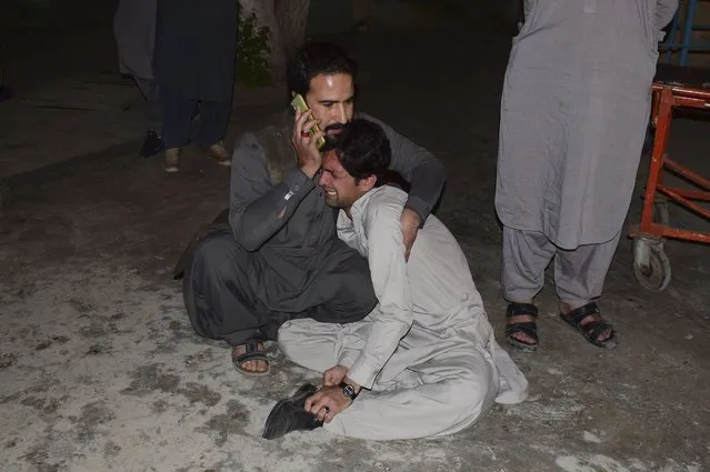 A Pakistani comforts to another mourning over the death of his family member in a bomb blast, at a hospital in Quetta, Pakistan, Wednesday, April 21, 2021. A powerful bomb went off in the parking area of a five-star Serena hotel in the southwestern city of Quetta on Wednesday, wounding some people, police said. (Photo by Arshad Butt/AP Photo)