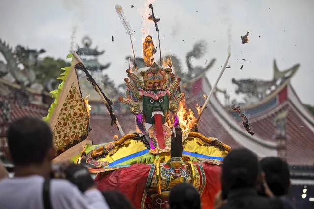 Ethnic Chinese people burn a “King of ghost” effigy during the Hungry Ghost Festival in Medan, North Sumatra, Indonesia, Wednesday, August 30, 2023. The festival is celebrated during the seventh month of the Chinese lunar calendar, when prayers are offered to the dead and offerings of food and paper-made models of items such as televisions and cars are burned to appease wandering spirits as it is believed that the gates of hell are opened during the month and the souls of dead ancestors return to visit their relatives. (Photo by Binsar Bakkara/AP Photo)