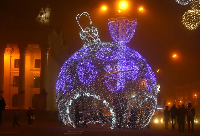 People are seen near a giant illuminated Christmas ball installed on Oktyabrskaya Square for the upcoming New Year and Christmas season in Minsk, Belarus December 21, 2016. (Photo by Vasily Fedosenko/Reuters)