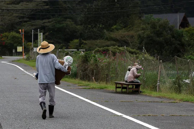 Masato Okaue, 71, carries a handmade human-sized scarecrow to be fixed in a field in the village of “Kakasi No Sato” on September 20, 2023 in Yasutomi, Japan. Masato Okaue, 71, has created human-sized scarecrows and placed them around his village to remind people that there are still 10 villagers who are 65 or older, who are still living there. Since 2010, he has set more than 130 scarecrows around farmlands, roadsides and abandoned houses to illustrate the old Japanese countryside and show that villages are not completely deserted. Due to dwindling birth rates and migration to urban areas, 8 houses are occupied among the 30 houses in the village and others are abandoned, which is emblematic of a similar phenomenon taking place across Japan. Japan's elderly population aged 65 and older reached a record high of 29.1%, according to the Internal Affairs and Communications Ministry statistics issued last Monday. (Photo by Buddhika Weerasinghe/Getty Images)
