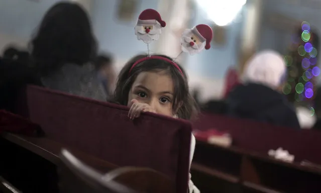A Palestinian Christian girl attends with her family, the prayers on Christmas Eve at the Holy Family Catholic Church in Gaza City, Saturday, December 24, 2016. (Photo by Khalil Hamra/AP Photo)