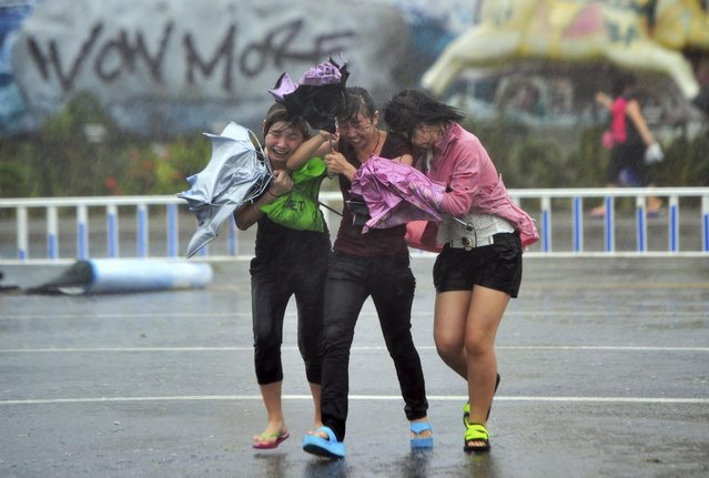 People cross a street against strong wind and heavy rainfall under the influence of Typhoon Haiyan, in Sanya, Hainan province November 10, 2013. One of the most powerful storms ever recorded killed at least 10,000 people in the central Philippines, a senior police official said on Sunday, with huge waves sweeping away entire coastal villages and devastating the region's main city. Despite weakening, the storm is likely to cause heavy rains, flooding, strong winds and mudslides as it makes its way north in the South China Sea. (Photo by Reuters/China Daily)