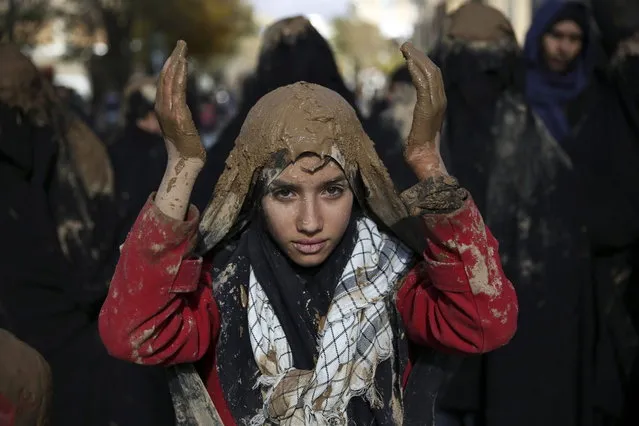 An Iranian Shiite covers her head with mud during Ashoura rituals, marking the death anniversary of Imam Hussein, the grandson of Islam's Prophet Muhammad, at the city of Bijar, west of the capital Tehran, Iran, Thursday, November 14, 2013. Hussein, one of Shiite Islam's most beloved saints, was killed in a 7th century battle at Karbala, Iraq. (Photo by Ebrahim Noroozi/AP Photo)