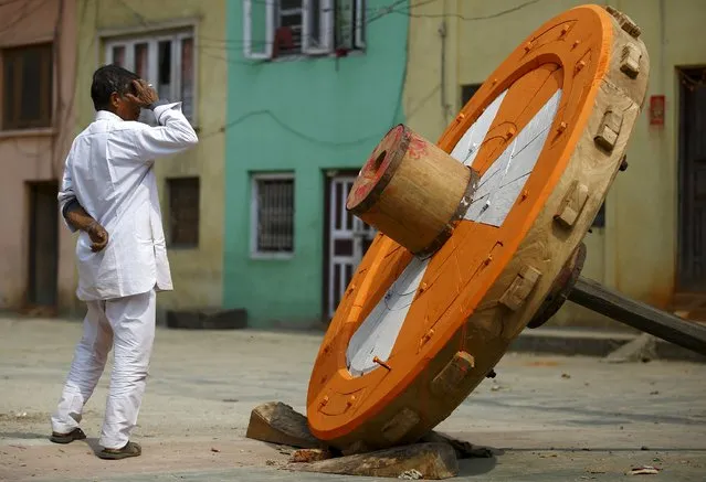 A man looks towards one of the four newly built wheel of the Rato Machhindranath chariot in Lalitpur March 23, 2015. The four wheels of the chariot are changed once in every twelve years. Rato Machhindranath is known as the god of rain and both Hindus and Buddhists worship Machhindranath for good rain to prevent drought during the rice harvest season. (Photo by Navesh Chitrakar/Reuters)