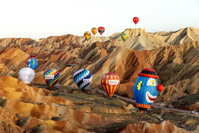 Colorful hot air balloons glide across the Qicai Danxia scenic area in Zhangye City, northwest China's Gansu Province on August 17, 2023. (Photo by Rex Features/Shutterstock)