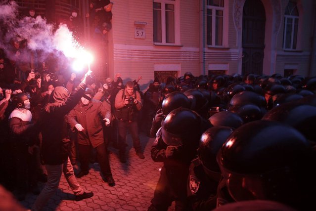 Protesters burn flares as they try to break through police lines near the presidential administration building during a rally held by supporters of EU integration in Kiev, December 1, 2013. Ukrainian opposition leader Vitaly Klitschko, addressing hundreds of thousands of protesters in central Kiev, called on President Viktor Yanukovich and his government to resign, saying they had “stolen” Ukraine's dream of European integration. (Photo by Stoyan Nenov/Reuters)
